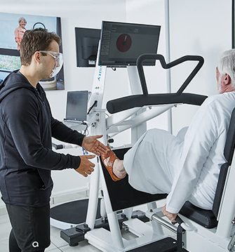 A trainer assisting a client with a leg on a biodensity machine